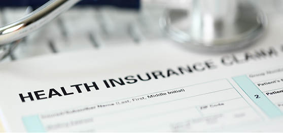 Letterbox view of stethoscope head and silver pen lying on application form at insurance agent worktable in company office closeup